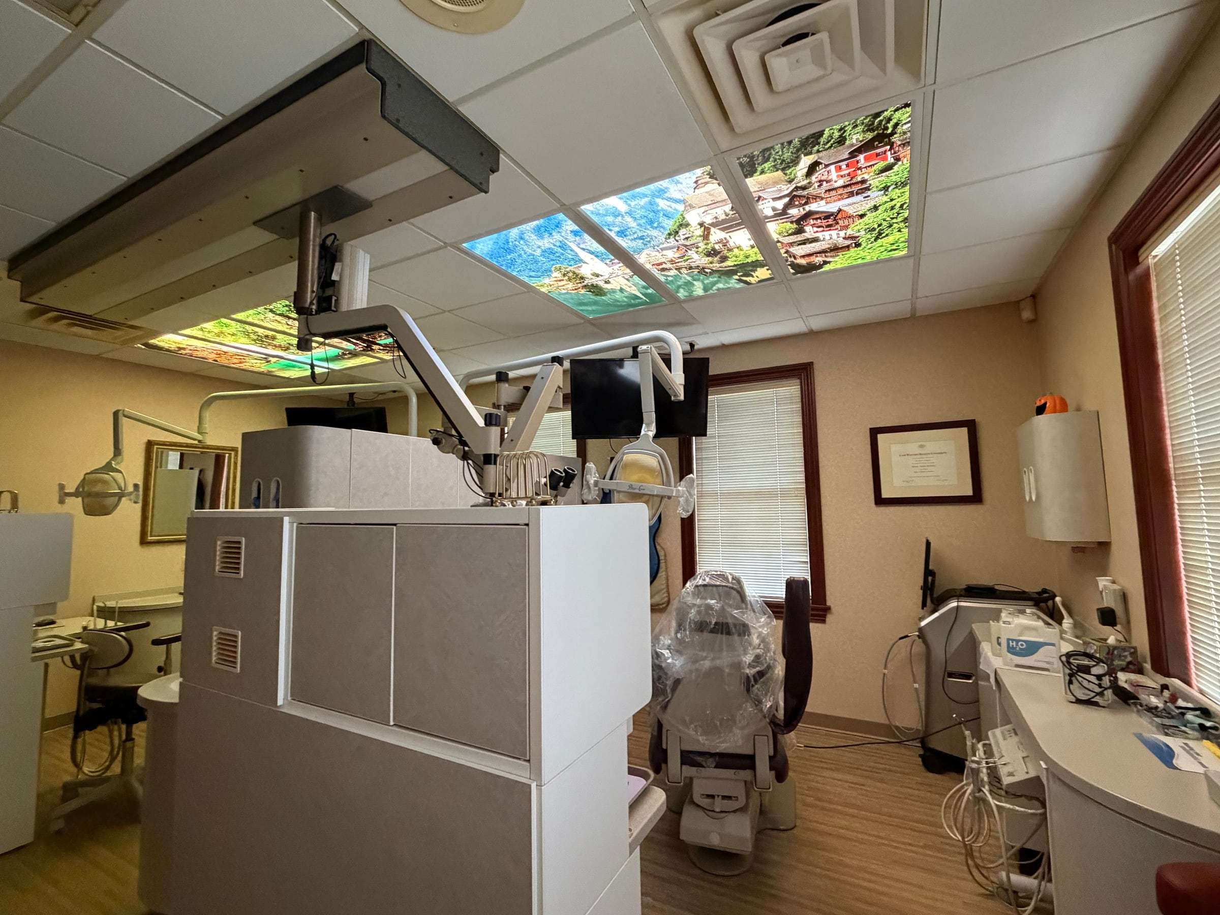 A treatment room with the surgical microscope over the chair and illuminated landscape panels in the ceiling